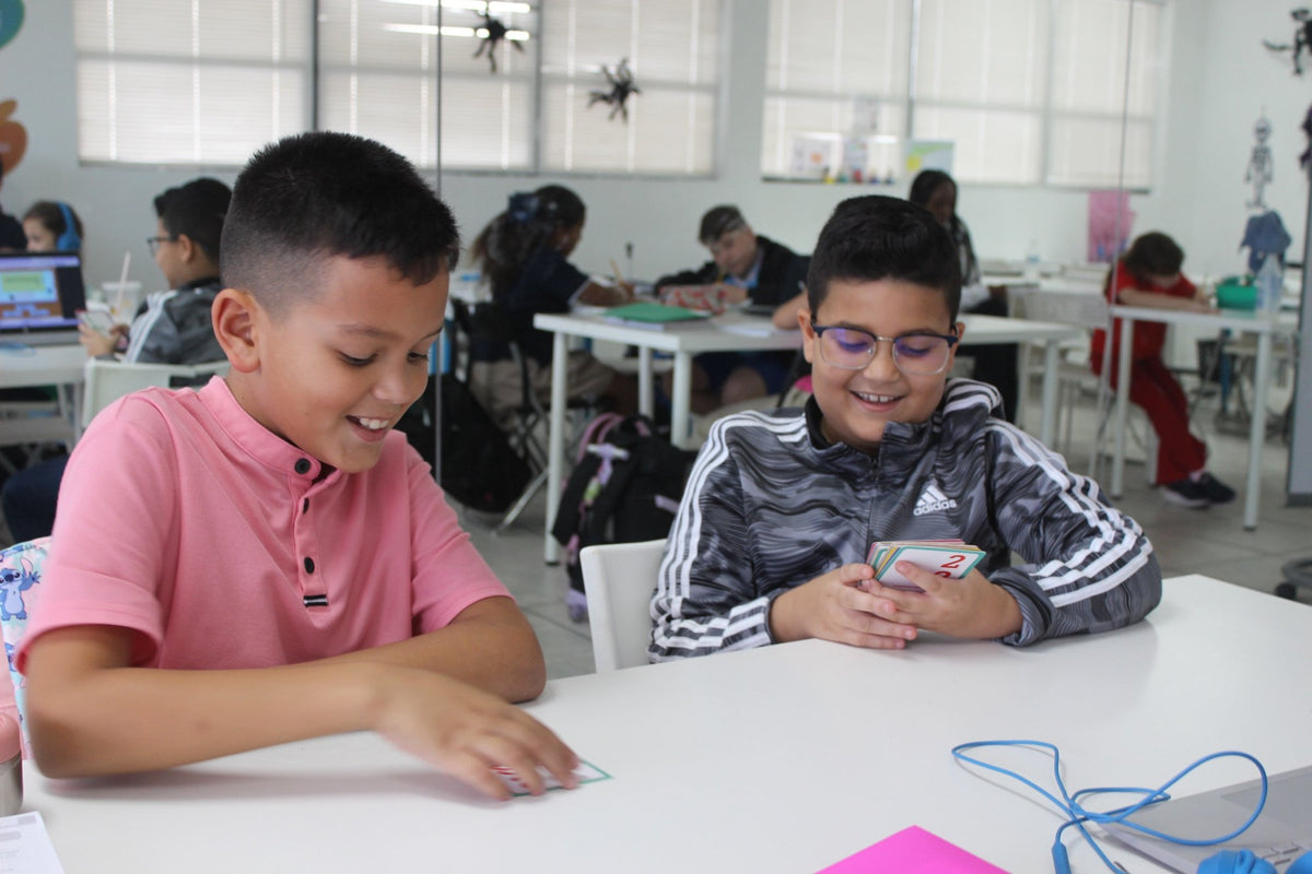 Dos estudiantes riéndose mientras practican con tarjetas didácticas en Open Mind Learning en Miami